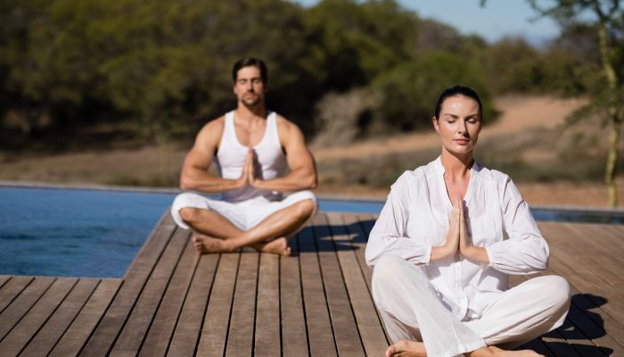 Couple performing yoga at safari vacation on a sunny day Couple performing yoga at safari vacation on a sunny day